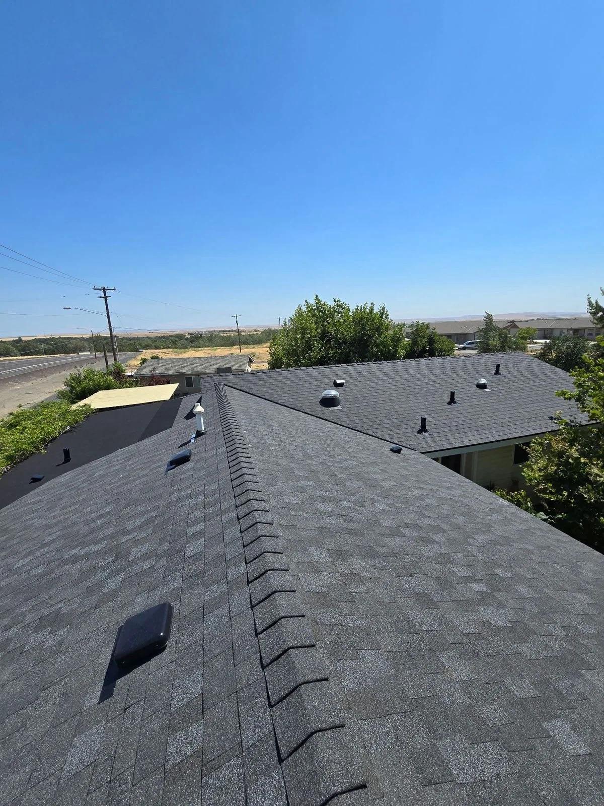 Finished charcoal shingle roof with ridge cap on Regina home, Makan Roofing
