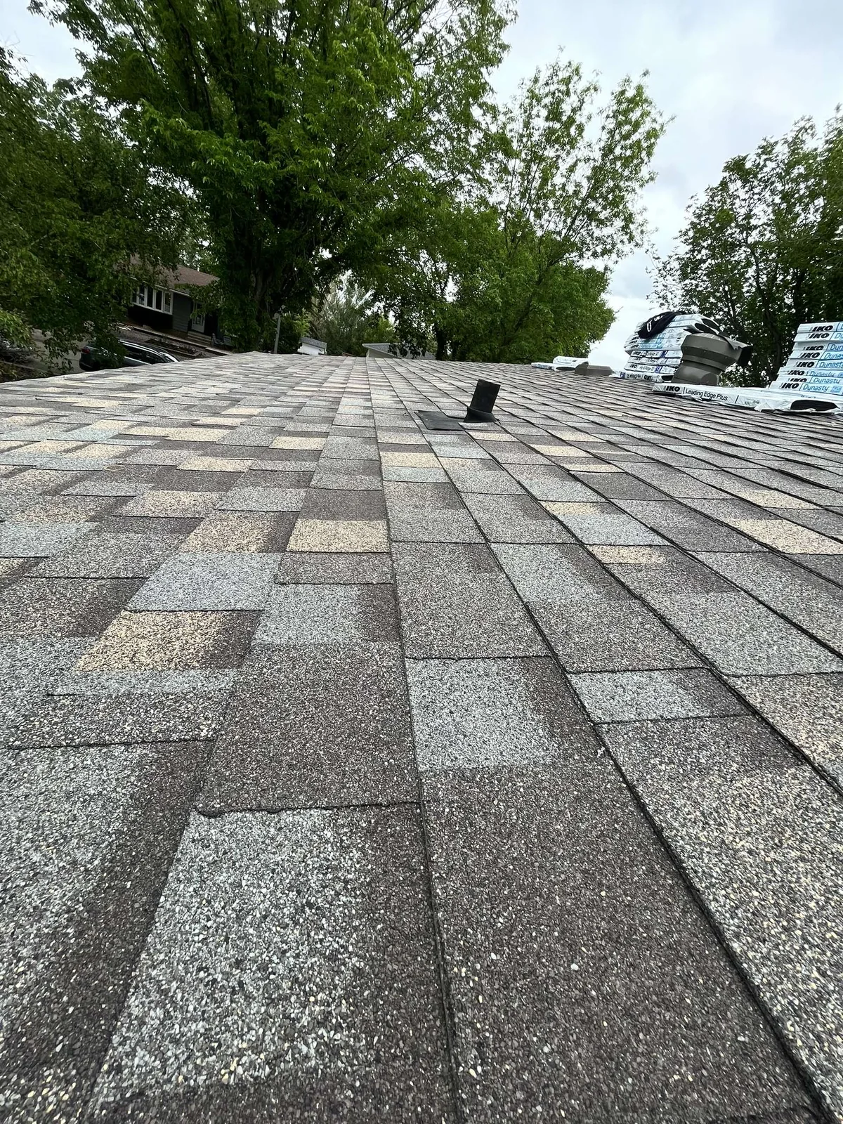IKO shingles being installed on Regina home by Makan Roofing, materials staged on roof
