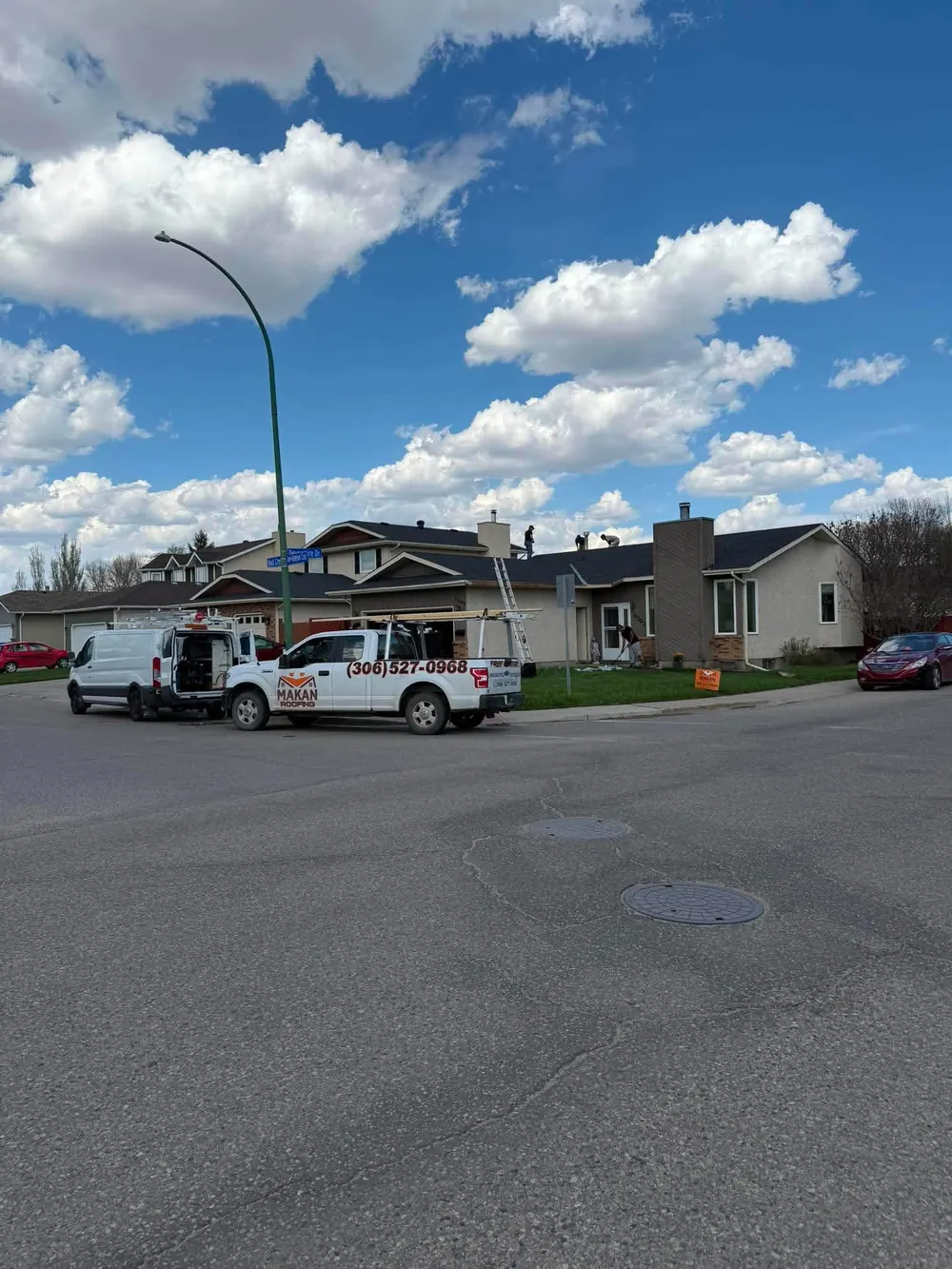 Makan Roofing trucks and crew at roof replacement job site in Regina Saskatchewan