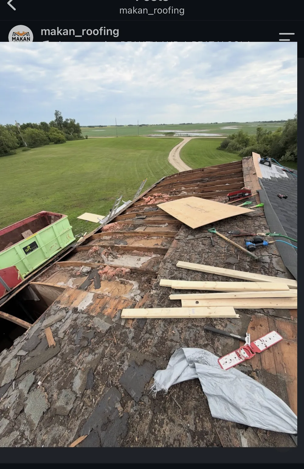 Makan Roofing crew tearing off old shingles from commercial quonset roof, exposed structure visible