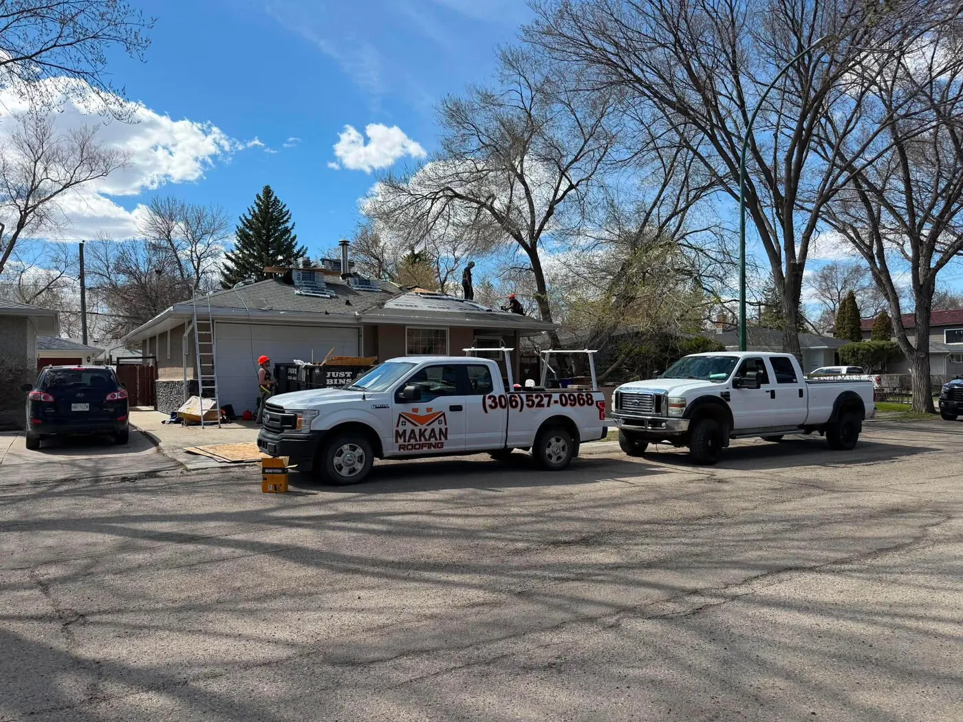 Makan Roofing branded work trucks at a roof replacement job site in Regina Saskatchewan